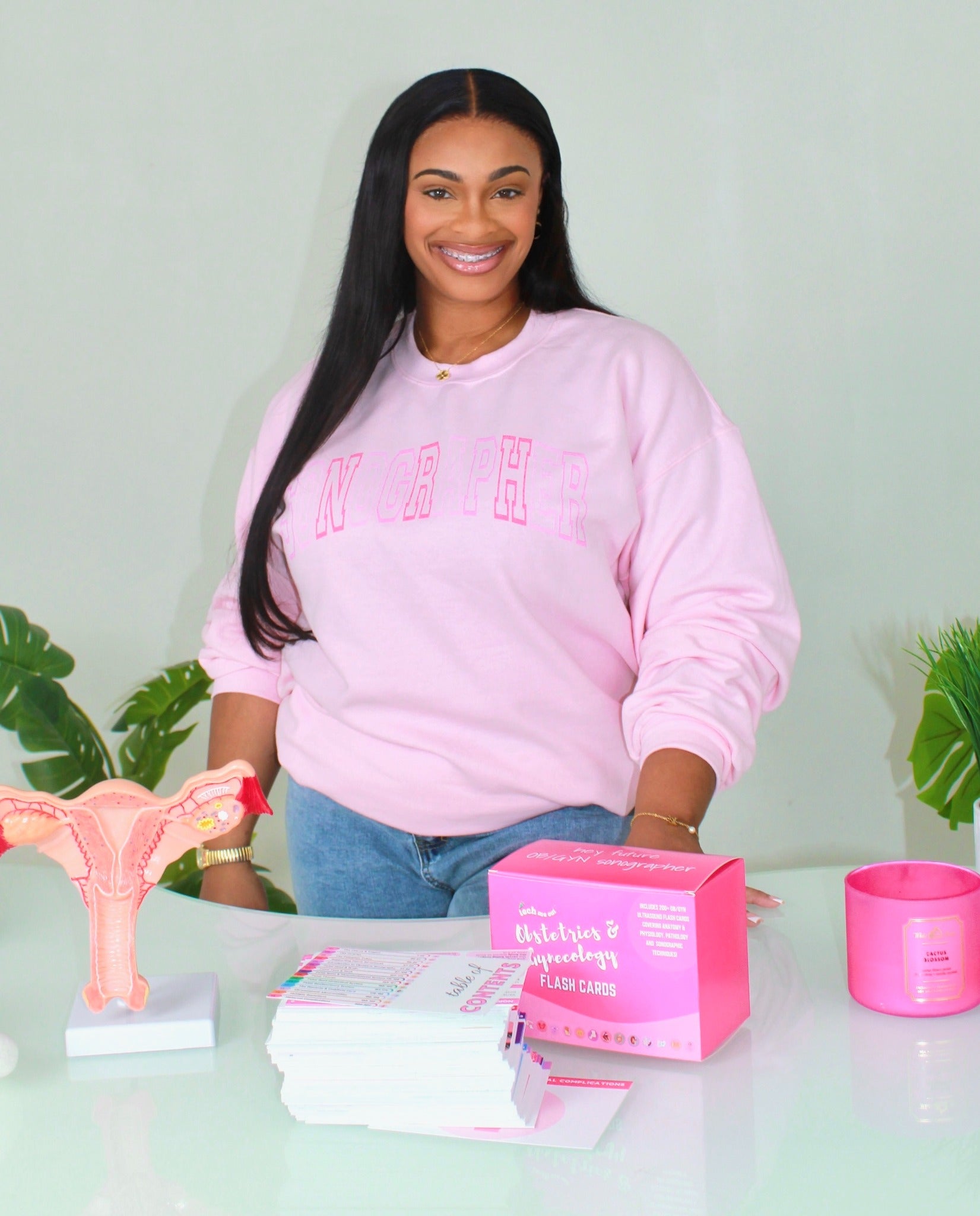Tekara, founder of Tech Me Out, wearing a pink sweatshirt with her study tools